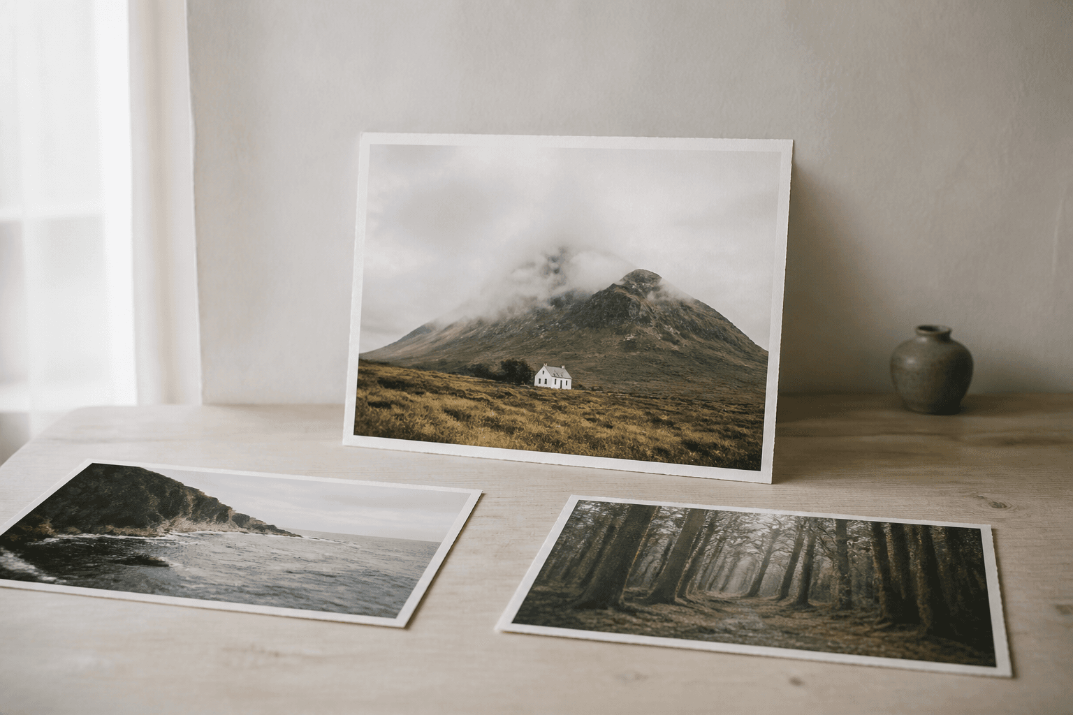 Three photo prints on a pale desk with one chosen print standing upright